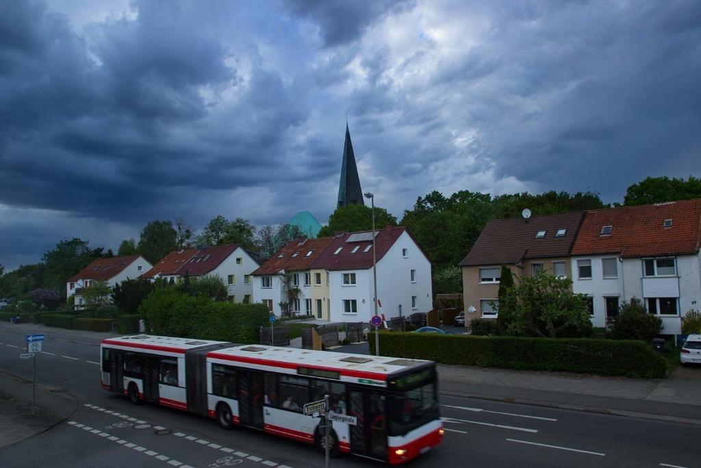 un autobús conduciendo por una calle con casas y una iglesia en Pension Wob en Wolfsburg