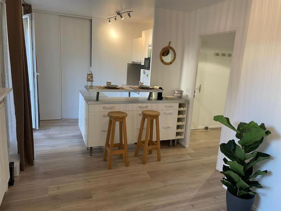 a kitchen with two bar stools and a counter top at Studio 28 m2 & jardin privatif 20 m2 in Montigny-le-Bretonneux