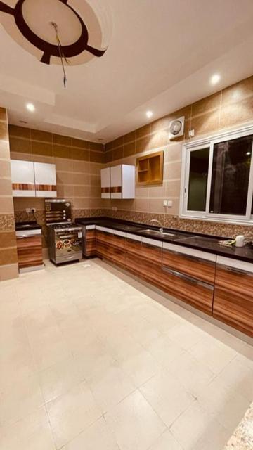 a large kitchen with wooden cabinets and a chandelier at شقق الأجواء الفاخرة in Al Madinah