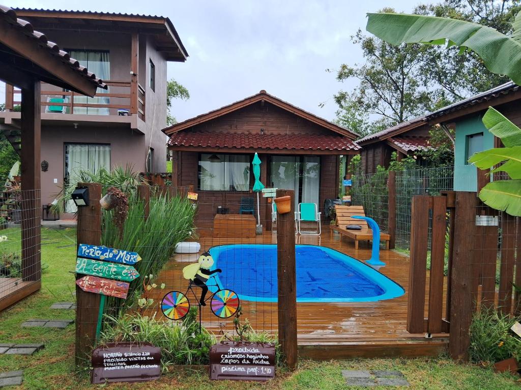 un patio trasero con piscina y una casa en Chalés Praia do Rosa piscina compartilhada en Imbituba