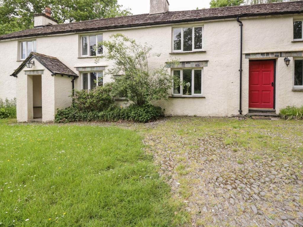 a white house with a red door and a yard at Hall Bank Cottage in Rydal