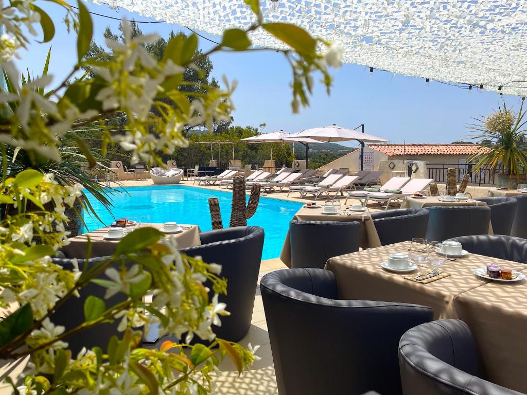 a restaurant with tables and chairs and a pool at Hotel & Appartements Acqua Dolce in Porticcio