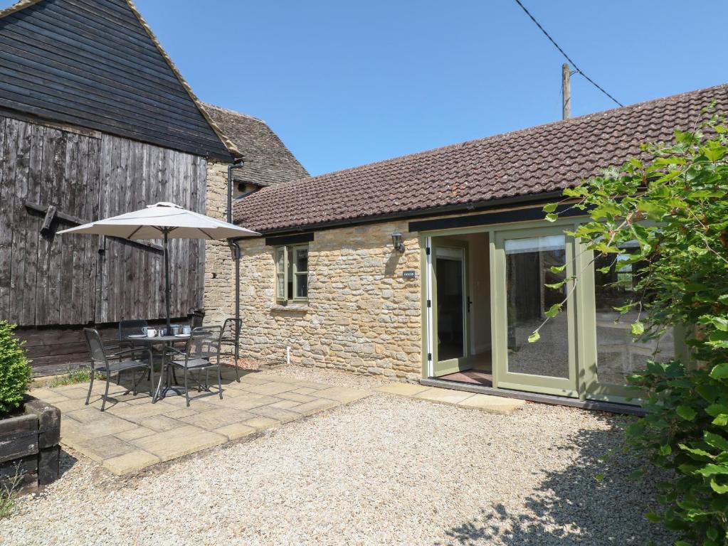 un patio con mesa y sombrilla en Ewecub Barn, en Burford