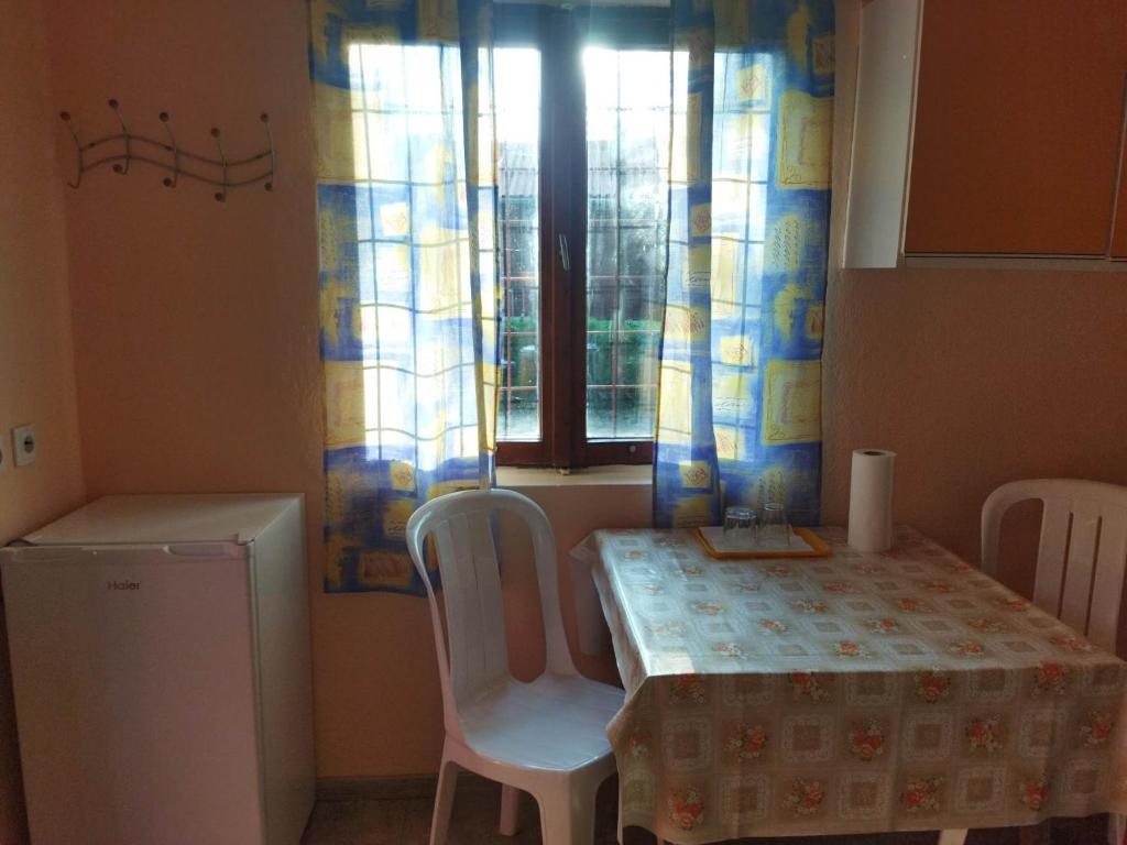 a kitchen with a table and chairs and a window at Mecsek Virágai Lak in Magyarhertelend