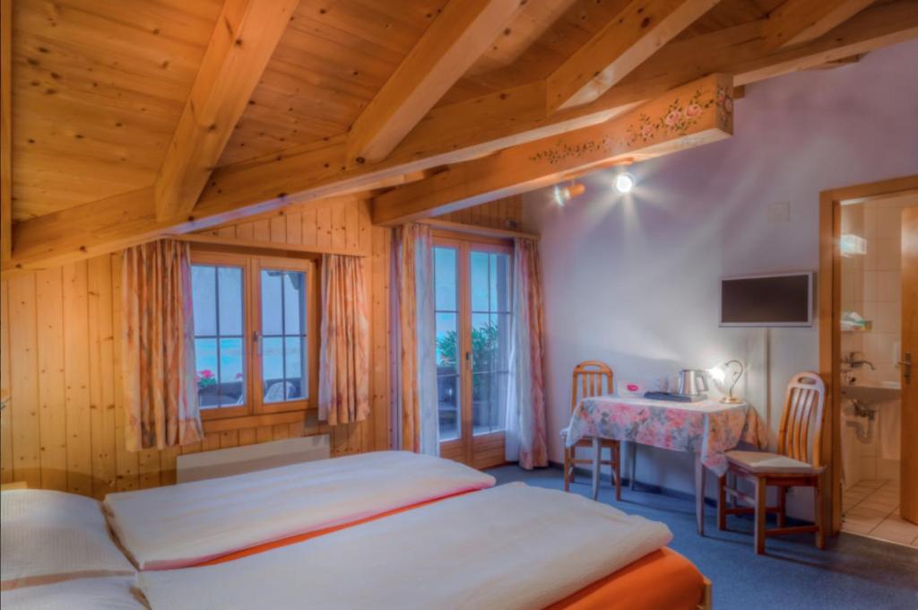 ein Schlafzimmer mit einem Bett und einem Tisch in einem Zimmer in der Unterkunft Hotel Wildbach Brienz in Brienz