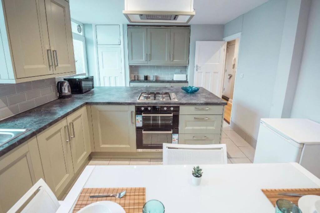 a kitchen with white cabinets and a stove top oven at 4 Bedroom in Finchley Road in London