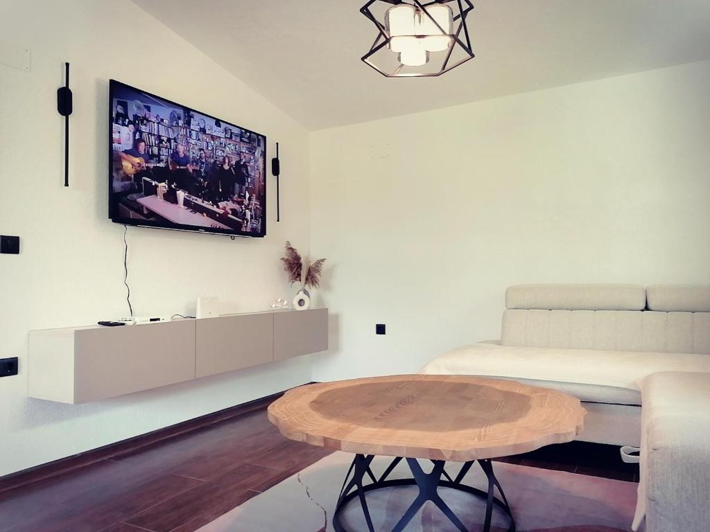 een woonkamer met een tafel en een tv aan de muur bij Vineyard Apartment in Ohrid