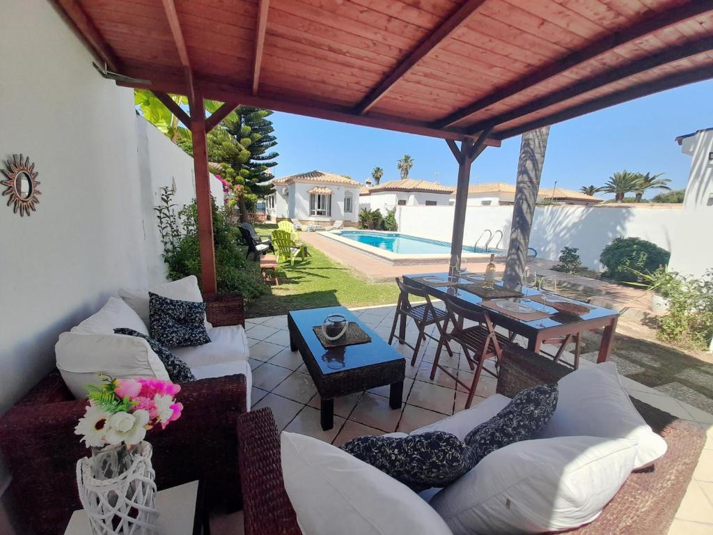 um pátio com sofás, uma mesa e uma piscina em Villa Lolera em Chiclana de la Frontera