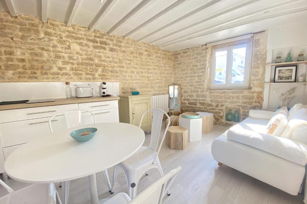 cocina y sala de estar con mesa y sofá en Charming little house with exposed stonework en Luc-sur-Mer