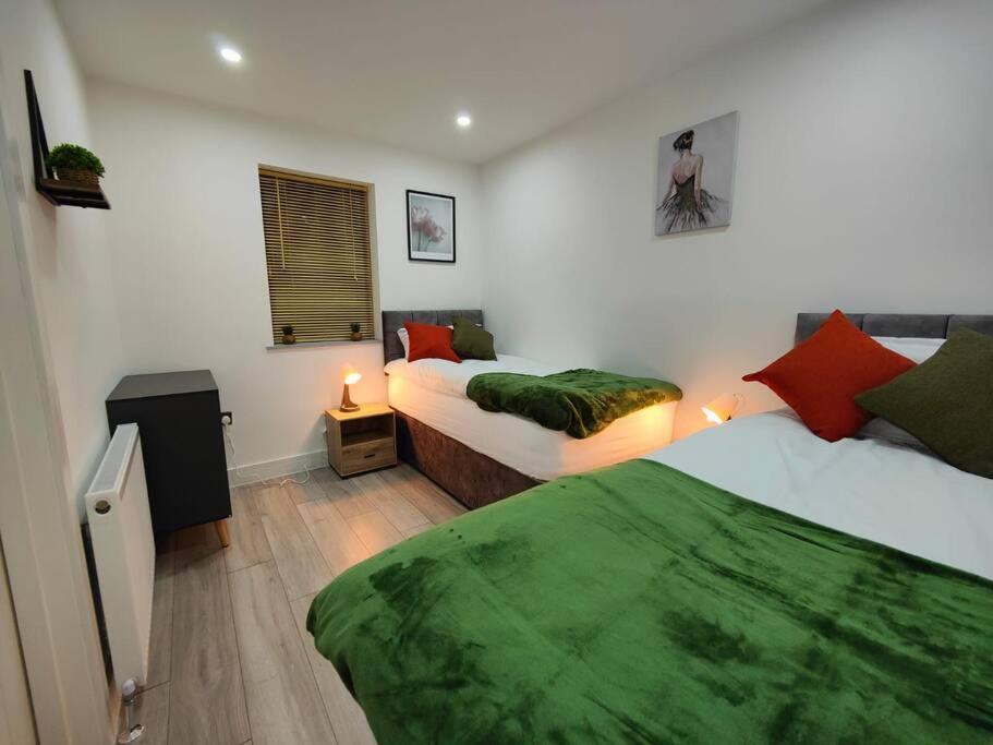 7 Guests - 4 Bedroom - Free Wi-Fi - Kettering في كيترينج: غرفة نوم بسريرين مع شراشف خضراء