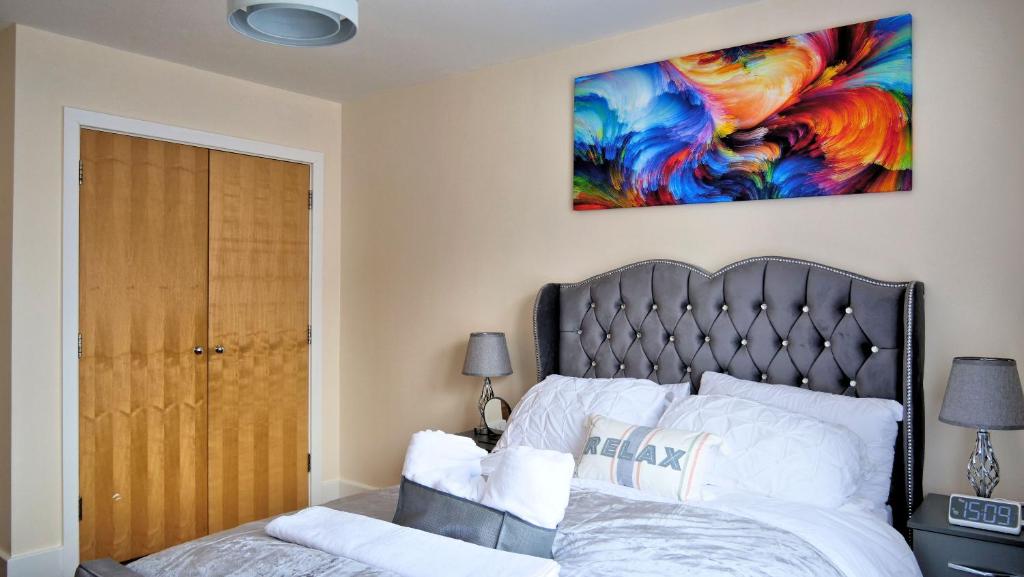 a bedroom with a bed and a painting on the wall at Keniji Luxury 2 Bed Apartment in Milton Keynes