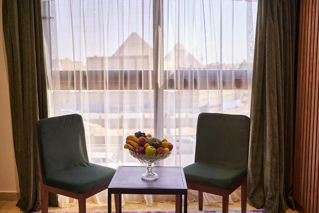 New Pyramid Front Hotel في القاهرة: مزهرية من الفاكهة على طاولة أمام النافذة