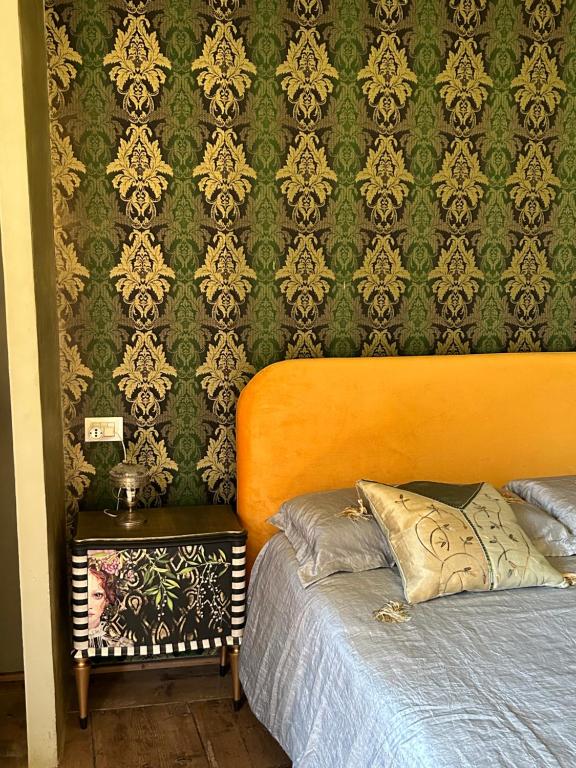 1 dormitorio con cama y papel pintado verde y dorado en La Maisonette, en Feltre