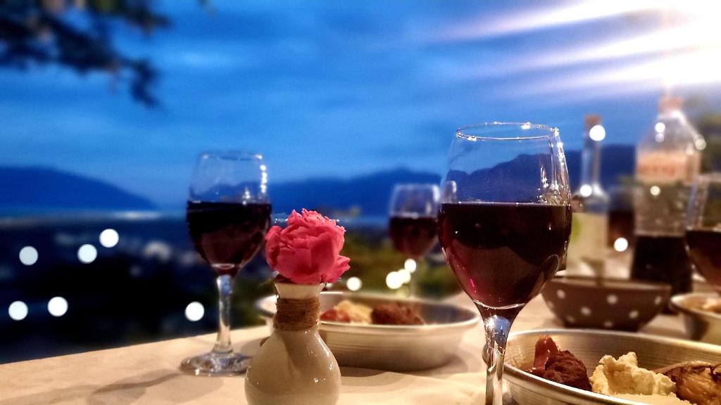 una mesa con tres copas de vino y comida en Clockwise GuestRooms en Gjirokastër
