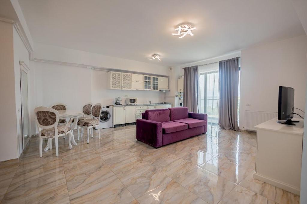 een woonkamer met een paarse bank en een keuken bij Miramare Apartament- Pool and Beach Resort in Mamaia Nord – Năvodari