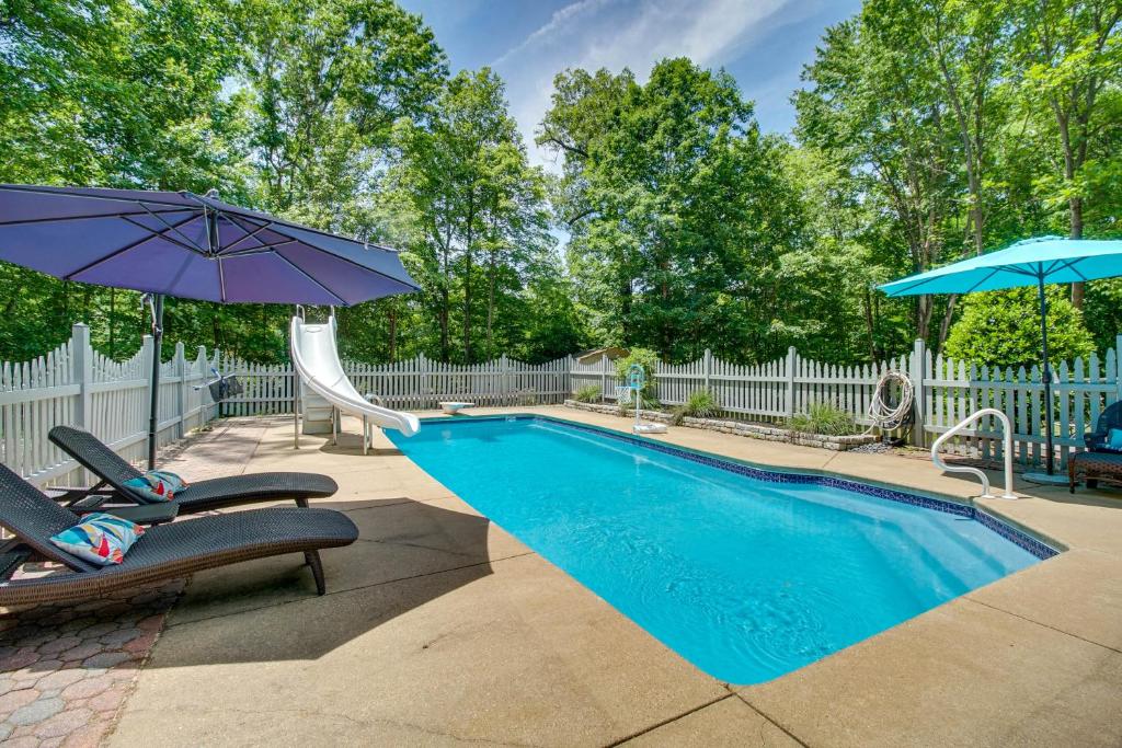 a swimming pool with two chairs and an umbrella at Cozy Virginia Vacation Rental with Seasonal Pool! in Nokesville