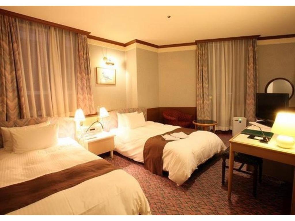 una camera d'albergo con due letti e una televisione di Hotel Sunlife Garden - Vacation STAY 55399v a Hiratsuka