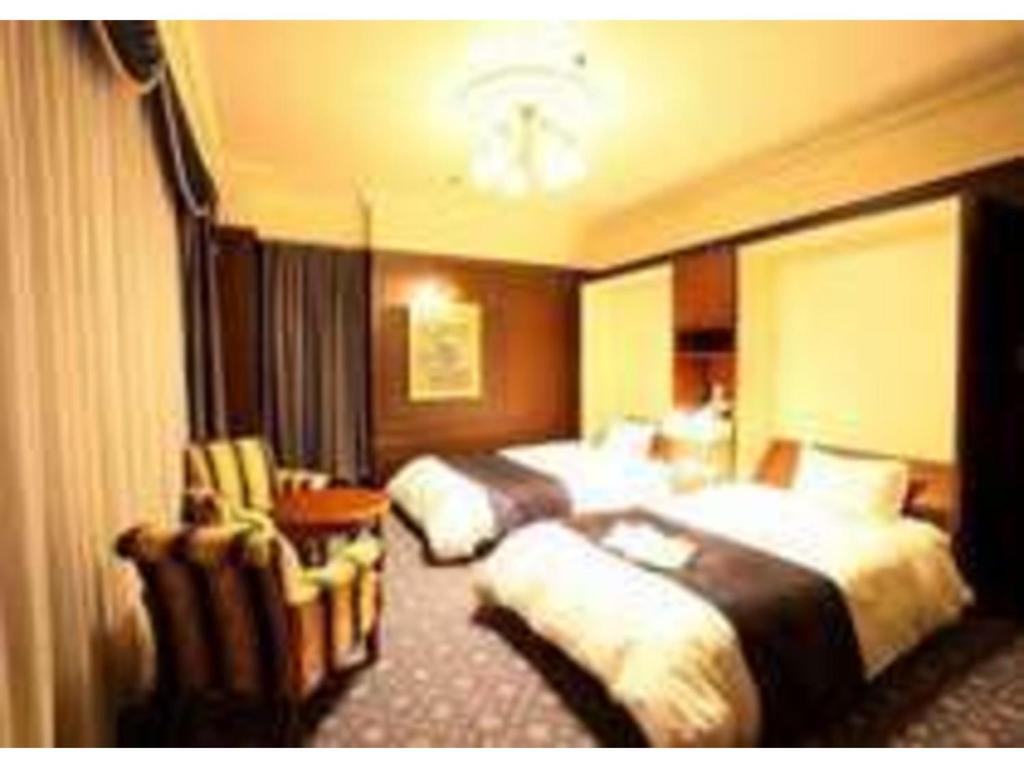 um quarto de hotel com duas camas e uma cadeira em Hotel Sunlife Garden - Vacation STAY 55416v em Hiratsuka