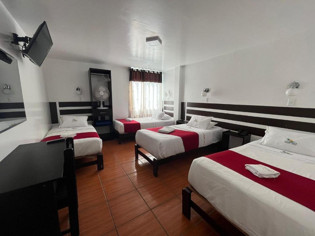um quarto de hotel com três camas e uma televisão de ecrã plano em HOTEL FIORELLA PARACAS em Paracas