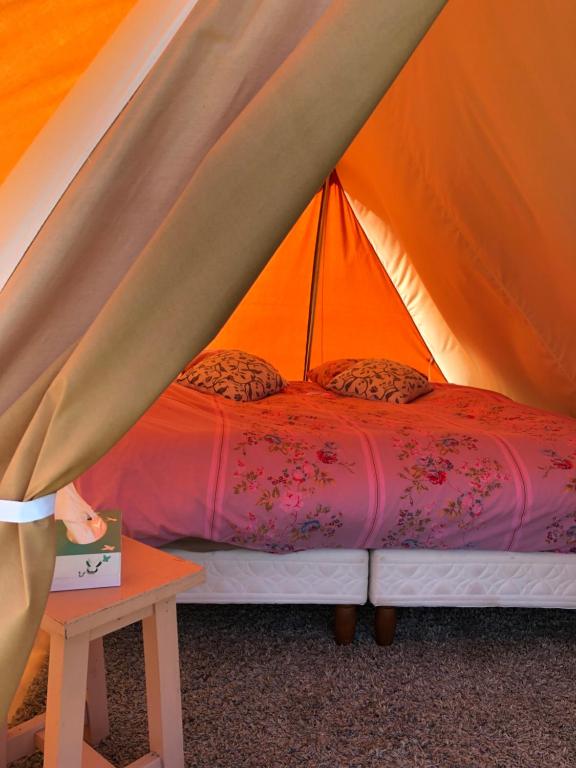 een bed in een tent met een tafel bij Tente bivouac Élevage Girbal in La Chapelotte