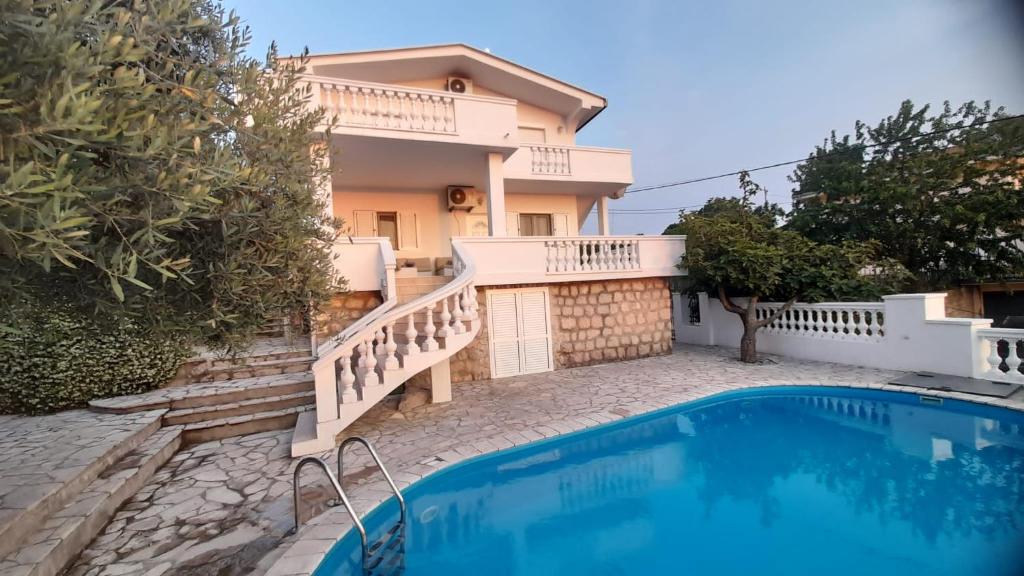 a villa with a swimming pool in front of a house at Villa Dedin in Utjeha