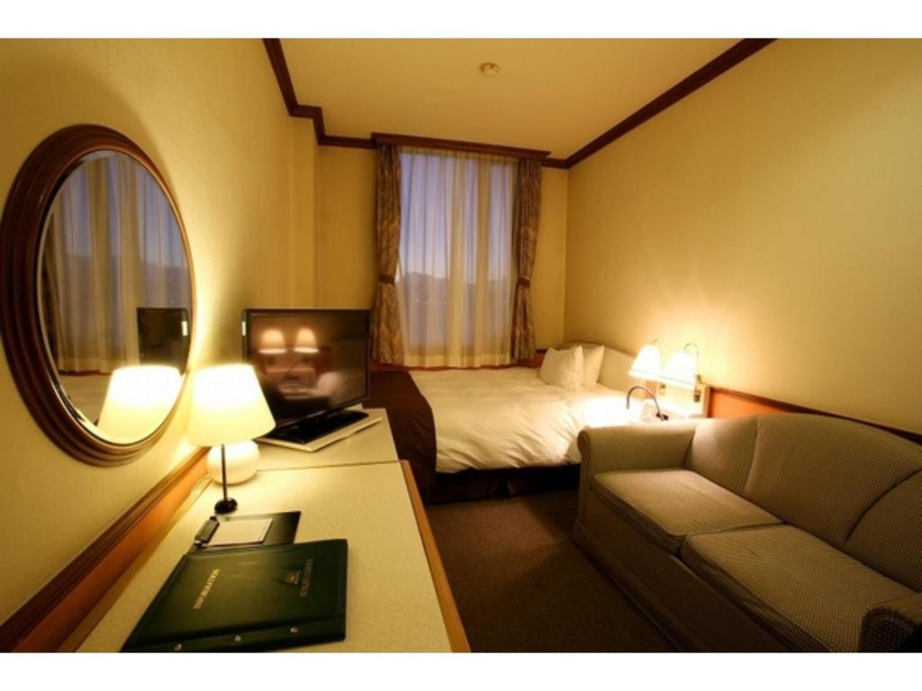 a hotel room with a bed and a couch at Hotel Sunlife Garden - Vacation STAY 55382v in Hiratsuka