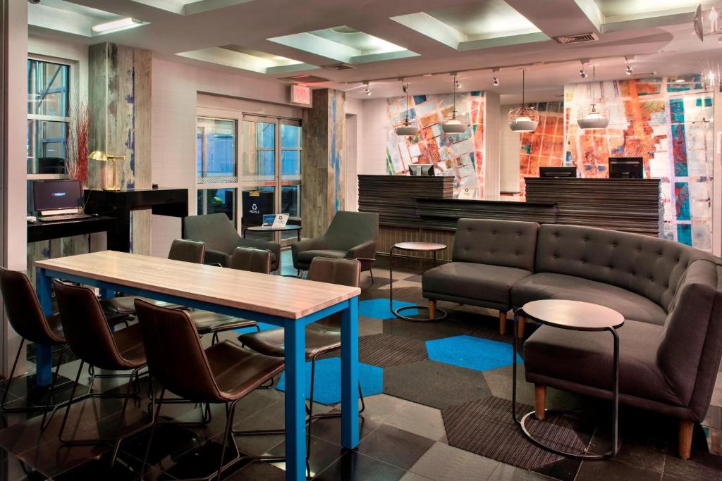 een wachtkamer met een tafel en stoelen en een bank bij Four Points by Sheraton Manhattan SoHo Village in New York