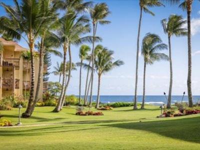 a golf course with palm trees and the ocean at Lae Nani Kauai in Kapaa