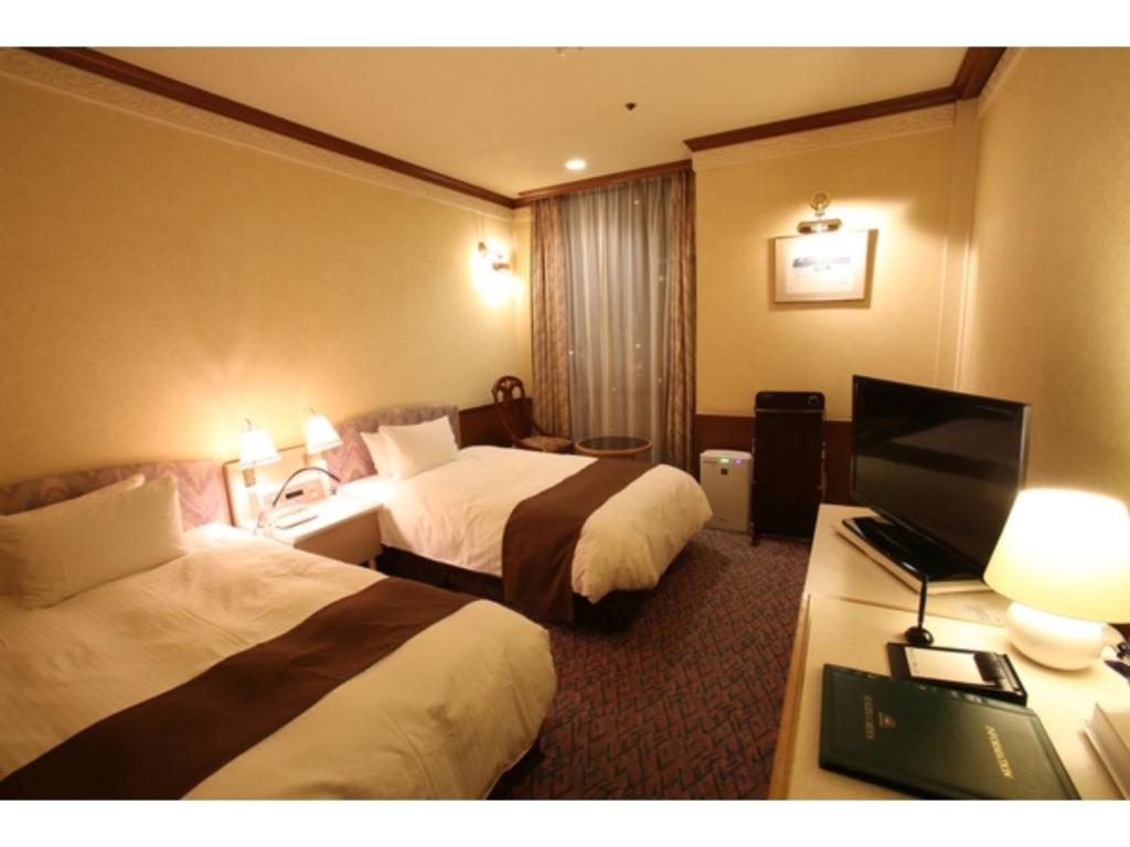 ein Hotelzimmer mit 2 Betten und einem Flachbild-TV in der Unterkunft Hotel Sunlife Garden - Vacation STAY 55396v in Hiratsuka