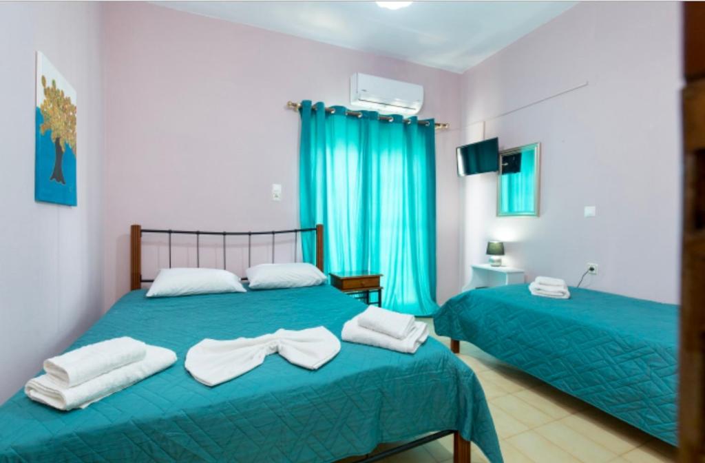 two beds in a room with blue curtains at Eleni in Kissamos