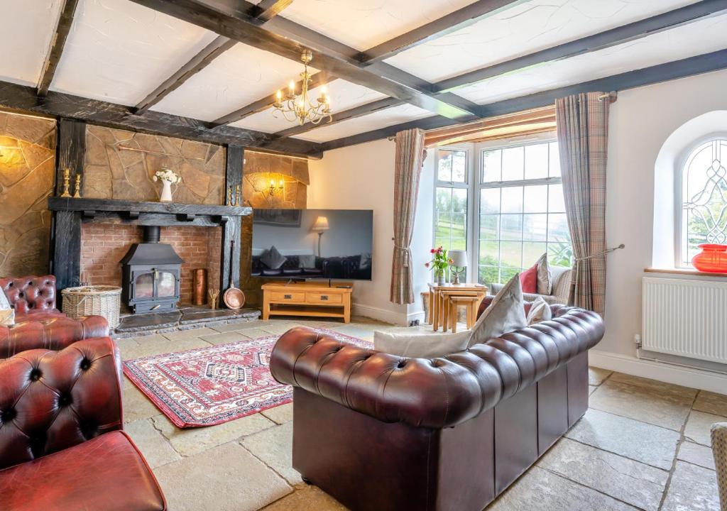 a living room with a leather couch and a fireplace at Hafod Ganol Farm in Trehafod