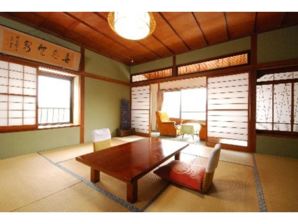 een woonkamer met een tafel, stoelen en ramen bij Kofukan - Vacation STAY 67971v in Myoko