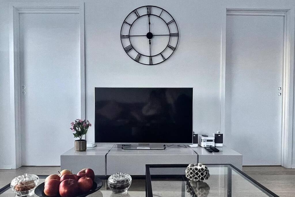 a living room with a tv and a clock on the wall at New Magnificent view apartment Near the centre in Tromsø