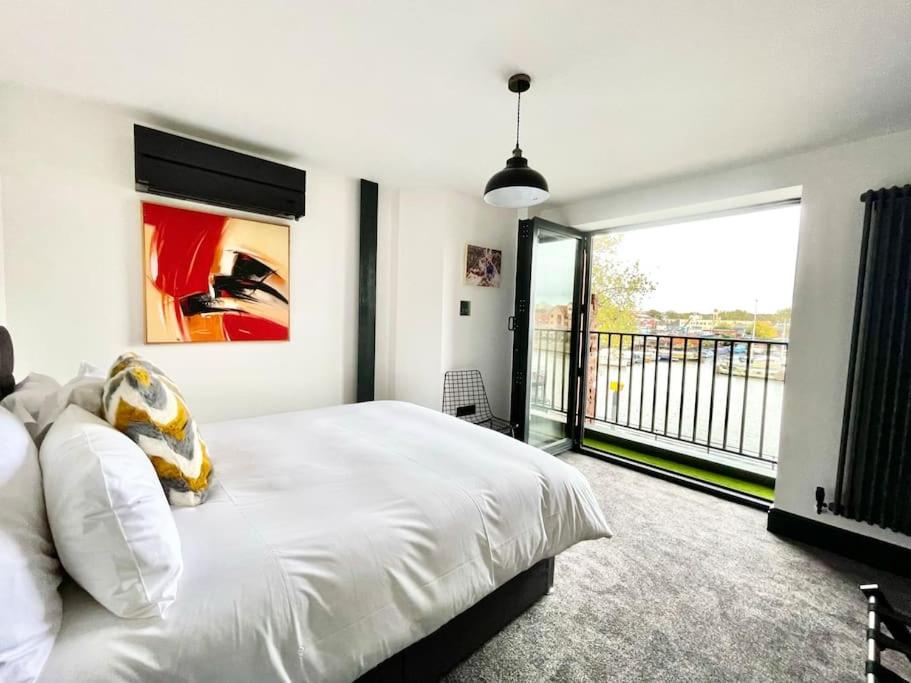a bedroom with a white bed and a large window at Duplex Apartment Harbourside city centre in Bristol