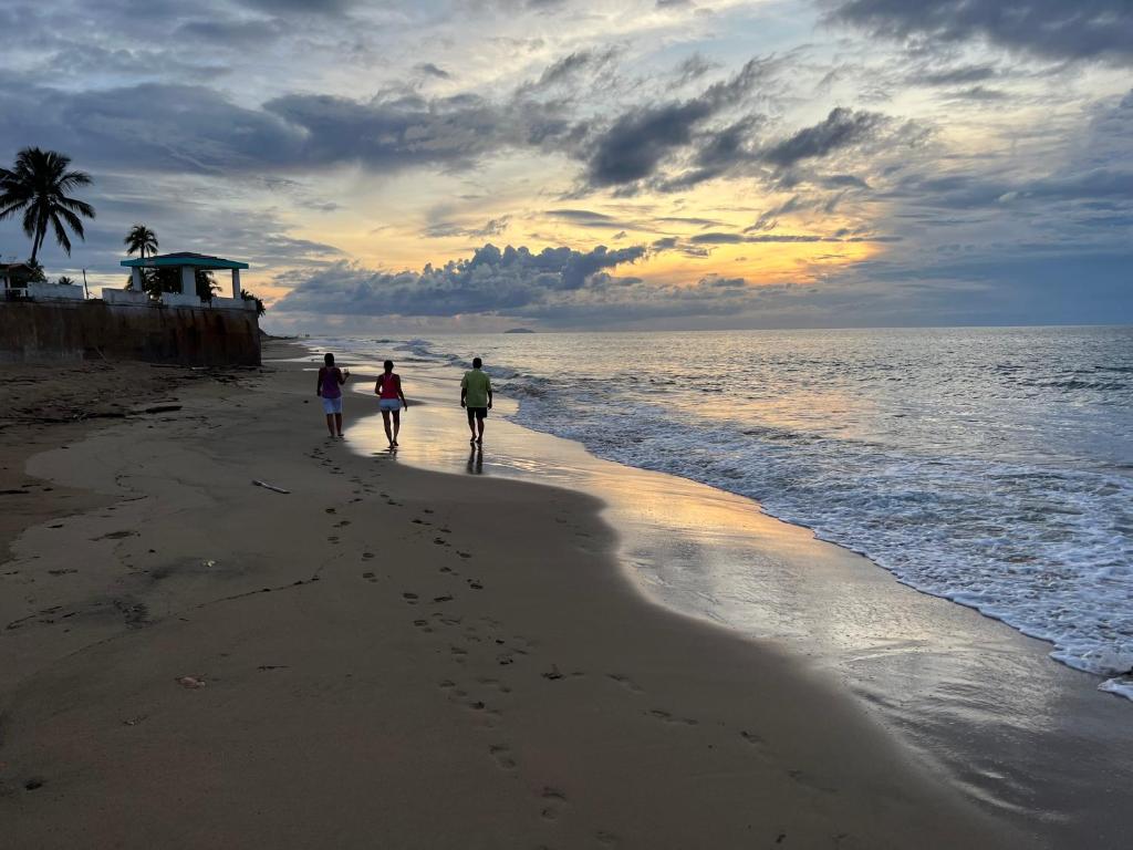 duas pessoas caminhando na praia ao pôr do sol em Aguada Beach Condos em Aguada