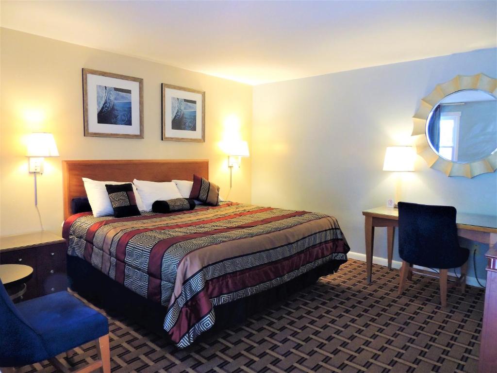 Habitación de hotel con cama, mesa y espejo en Windsor Motel en Groton