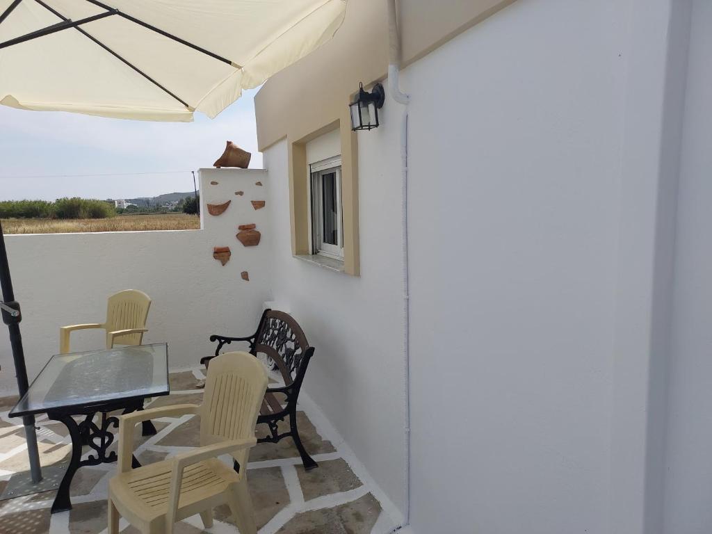 a patio with chairs and a table and an umbrella at Small houses anna&sofos in Kardamaina