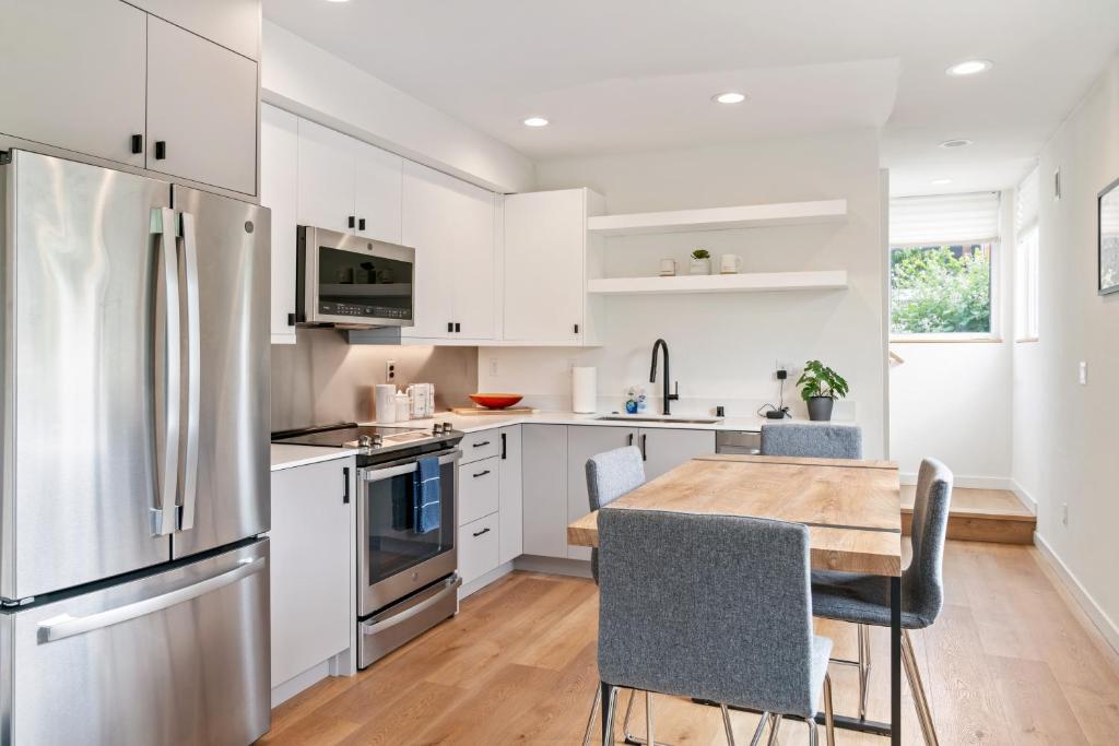 a kitchen with white cabinets and a wooden table with chairs at Modern two story townhouse near light rail in Seattle