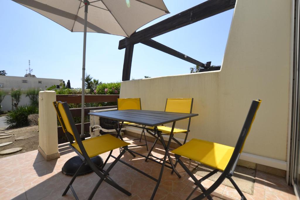 a table and chairs on a patio with an umbrella at Studio Naturiste "JUL'S"Port Nature 401 in Cap d'Agde