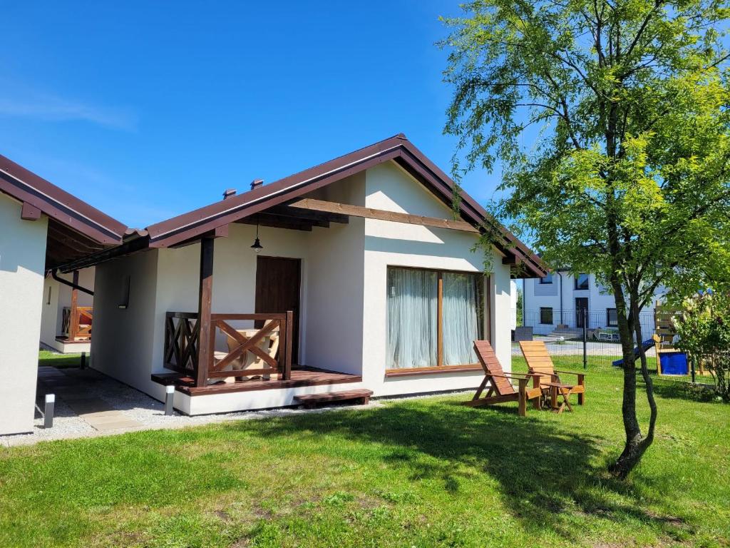 a small white house with two chairs in a yard at Domki Oaza Spokoju in Władysławowo
