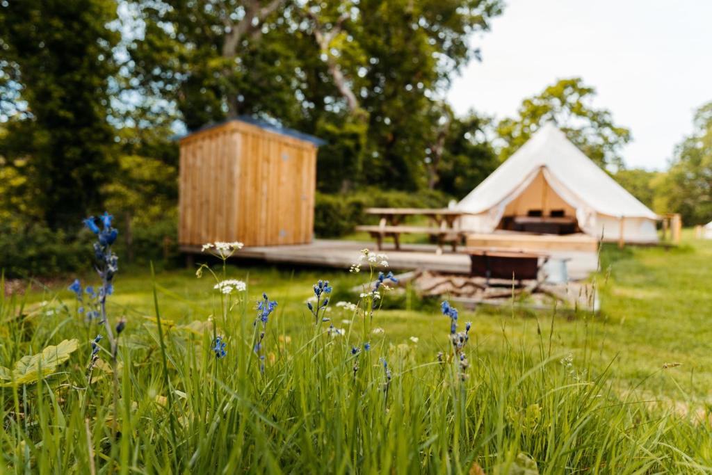 a yurt with a picnic table and flowers in a field at Cefn Crib Glamping in Machynlleth