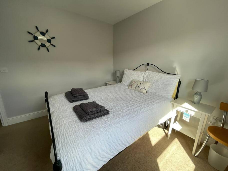 una camera da letto con un letto bianco e asciugamani di Braunton Breaks - South Break House a Braunton