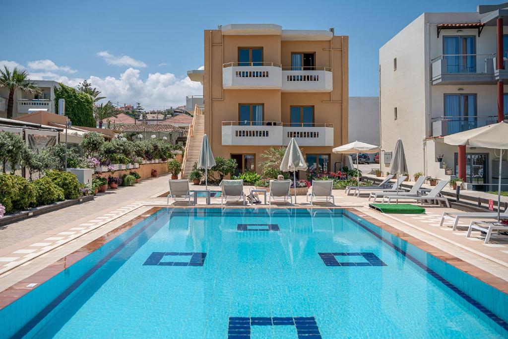 una gran piscina con sillas y un edificio en Esperides Beach Hotel Apartments, en Stalós