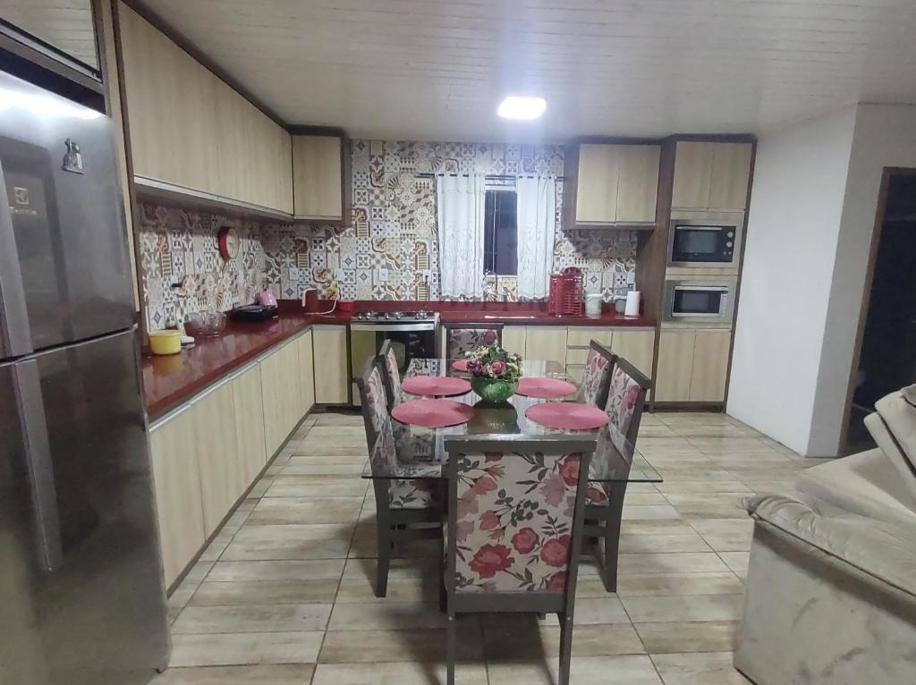 eine Küche mit Tisch und Stühlen mit rosa Kissen in der Unterkunft Casa no centro de Urubici Dutra Borba in Urubici