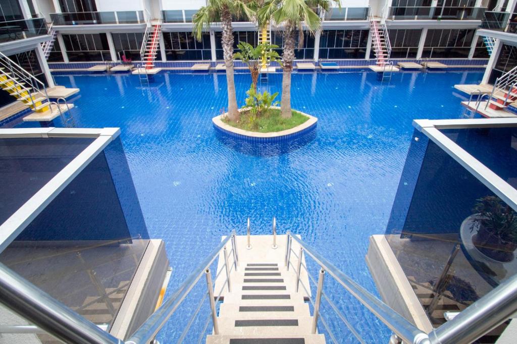 a large blue swimming pool with palm trees in a building at Antalya Lara Dubleks 2+1 in Altınkum
