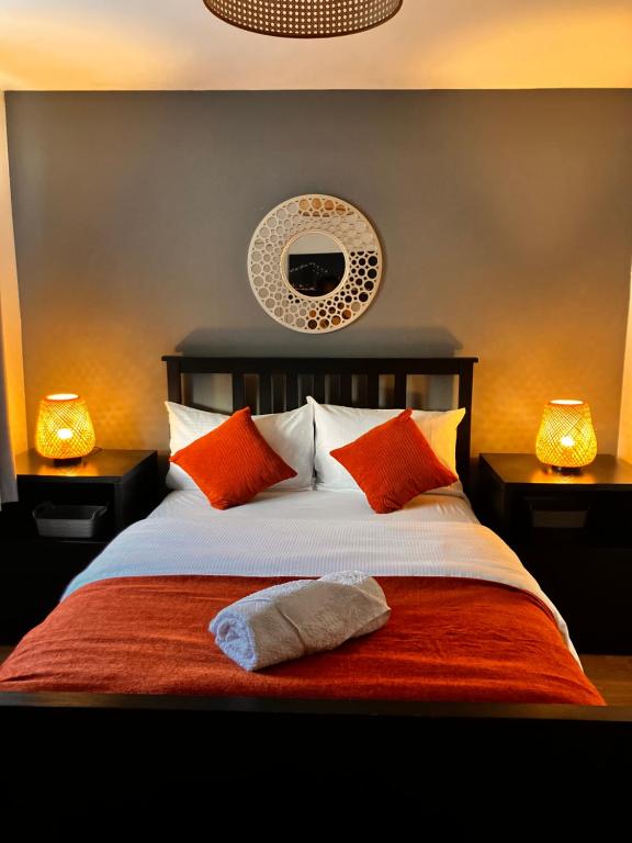 a bedroom with a bed with orange pillows and two lamps at Urban Escape Glasgow Green Free Parking 15min walk to City Center in Glasgow