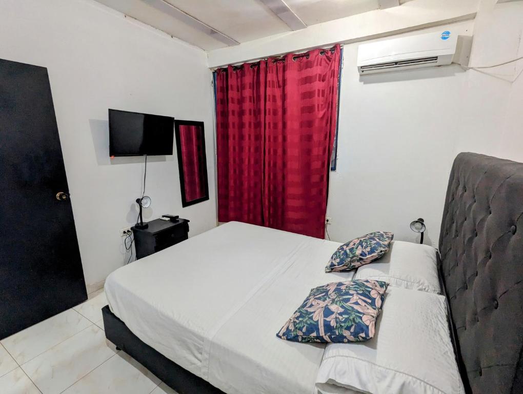 1 dormitorio con cama y cortina roja en Casa Bautista Apartamentos Amoblados con vista al mar, en Taganga
