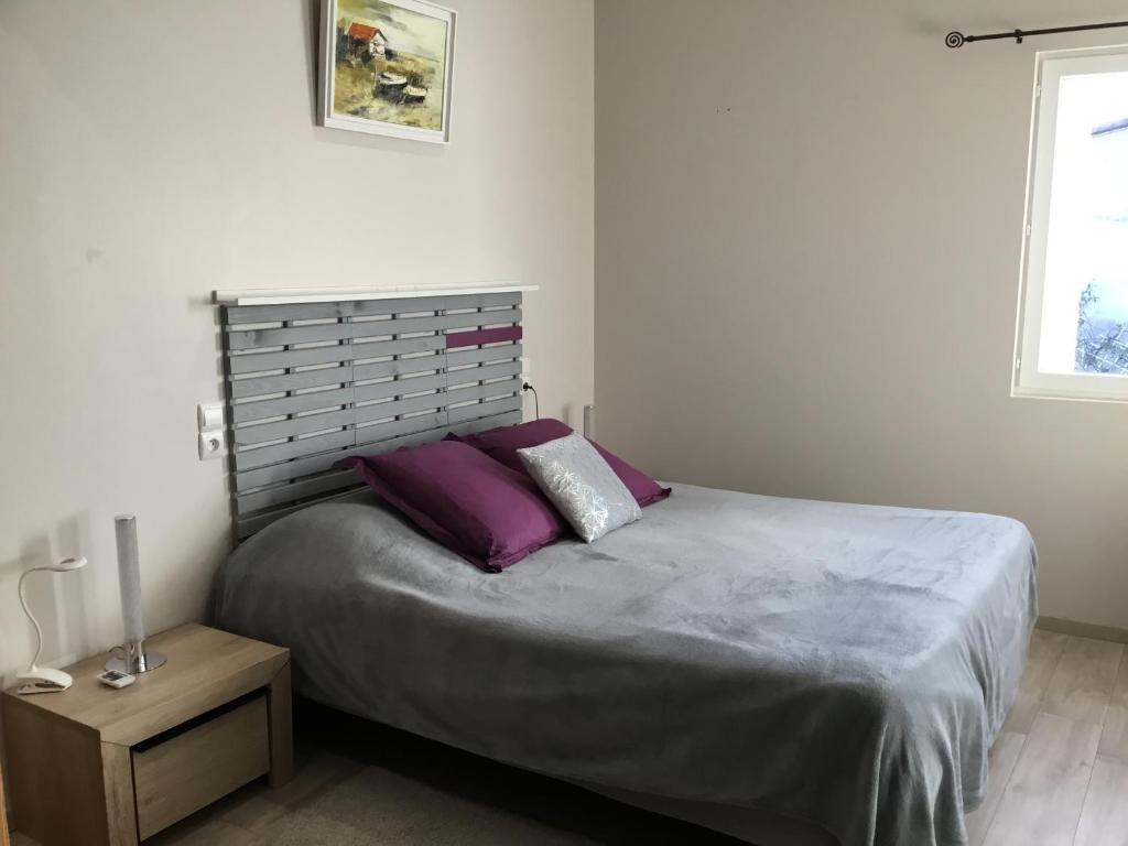 a bedroom with a large bed with purple pillows at Maison de Louna in Noailles