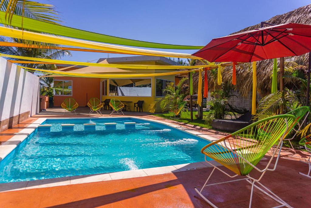- une piscine avec un parasol rouge et des chaises dans l'établissement Casa grande Monterrico, à Monterrico