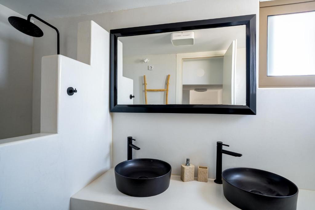a bathroom with two black sinks and a mirror at Saint Nicholas Resort - Villas in Kithnos
